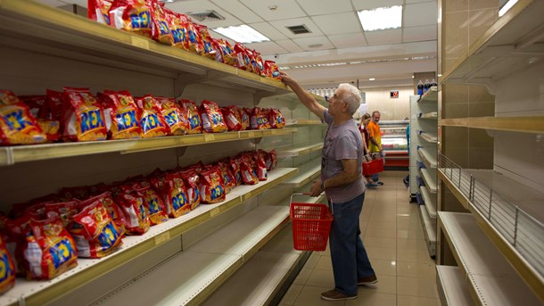 TOMME HYLDER:  En mand på indkøb i et supermarked i Caracas, Venezuela, hvor den eneste tilgængelige vare er småkager. [Foto: Ariane Cubillos/Ritzau Scanpix].