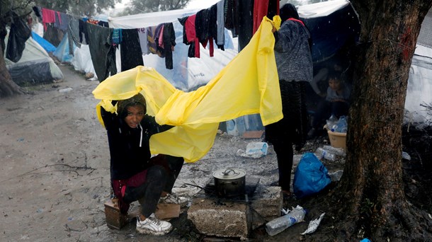 Ung pige, der skærmer sig mod regnen, uden for flygtningelejren Moria på den græske ø Lesbos. 