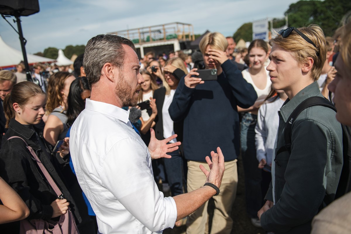 Jakob Ellemann-Jensen omringes af unge mennesker i det øjeblik, han træder ned fra ølkassen. Der er rift om partilederen og statsministerkandidaten til både interviews og selfies. Pladsen var fyldt, da han holdt sin korte tale. 