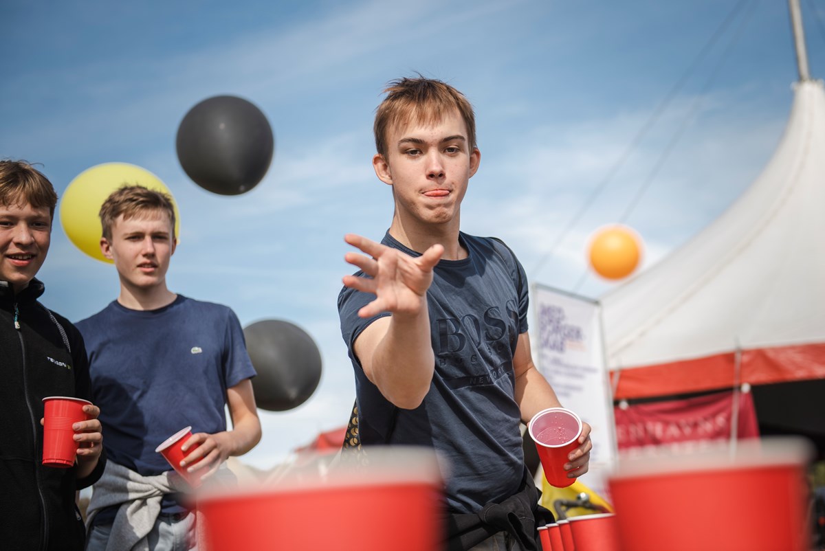 Hos Unge Ravne spilles sodavands-pong. Spillet bliver afbrudt af en quizmaster: 