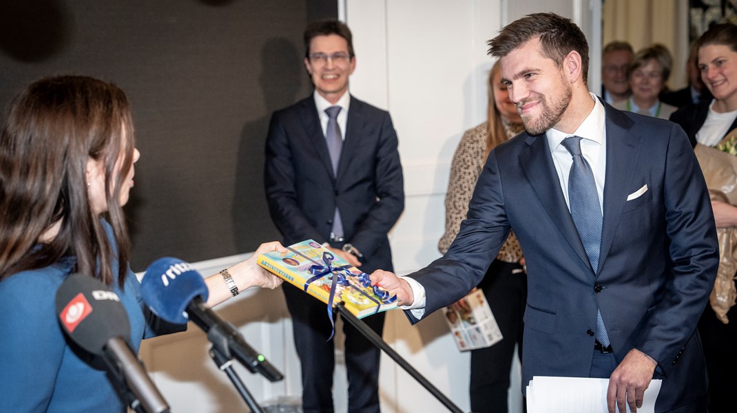 Afgående kirkeminister Louise Schack Elholm giver afløseren Morten Dahlin bogen 