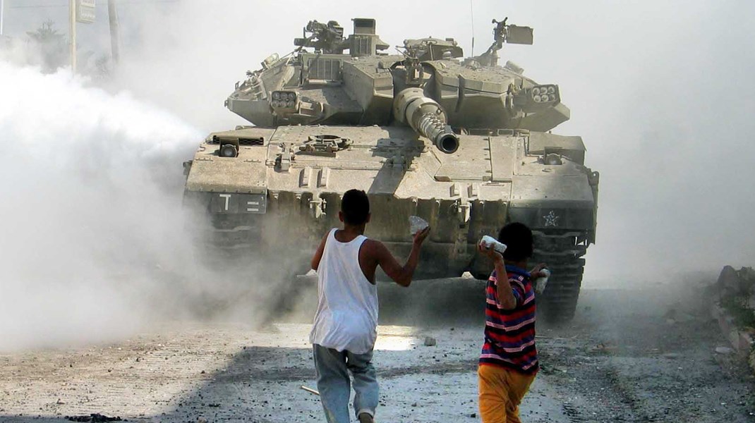 Palæstinensiske børn kaster sten mod en israelsk tank på i byen Jenin på Vestbredden august 2003.